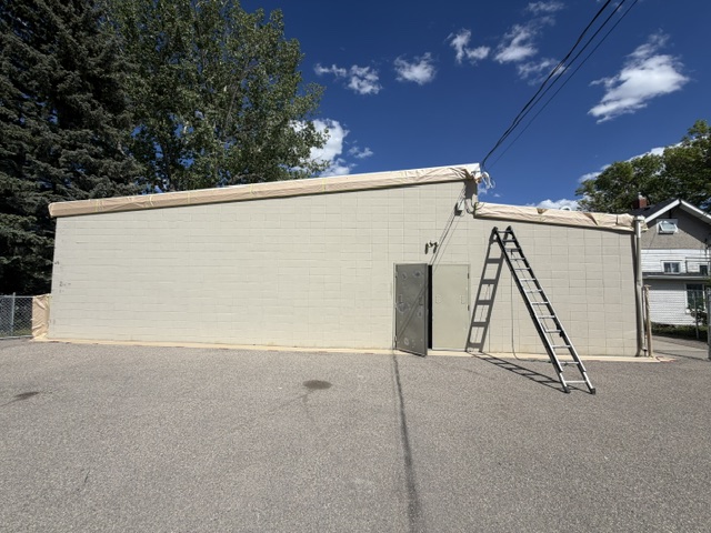 Beige block commercial building masked before painting